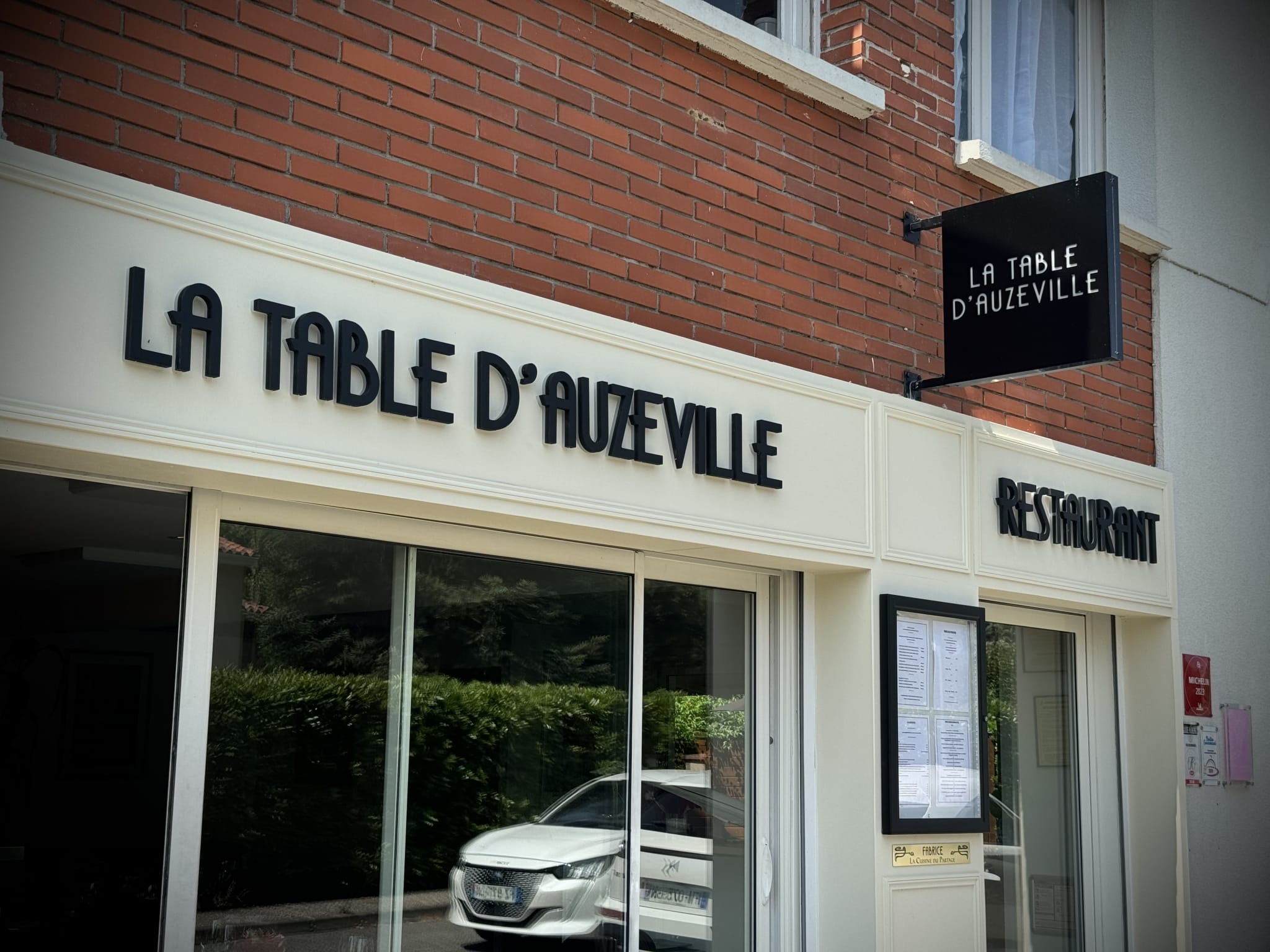 Enseigne lumineuse restaurant La Table d'Auzeville à Toulouse – vue de l'entrée avec panneau drapeau rétro-éclairé