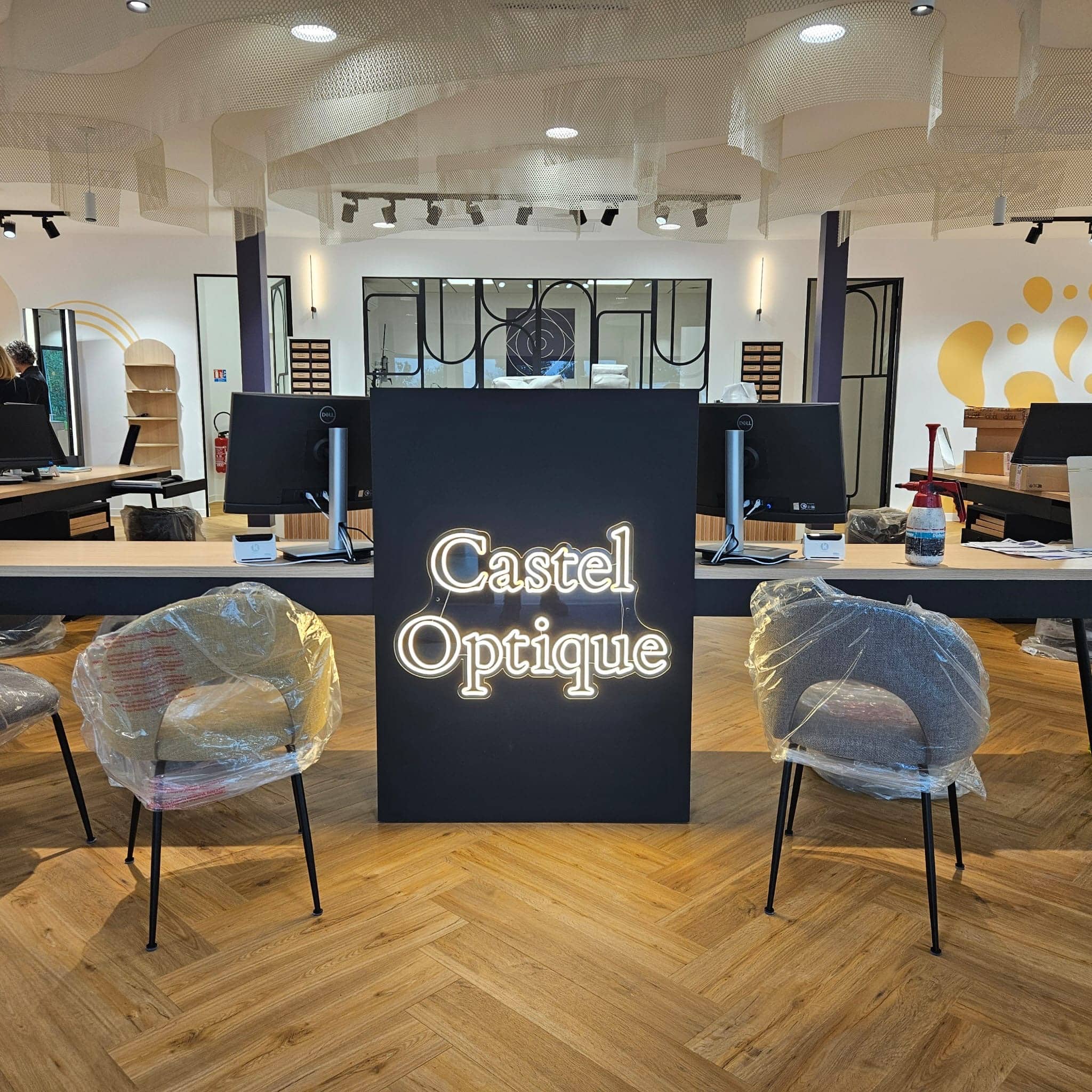 Logo lumineux Castel Optique installé en façade de comptoir dans un magasin d’optique
