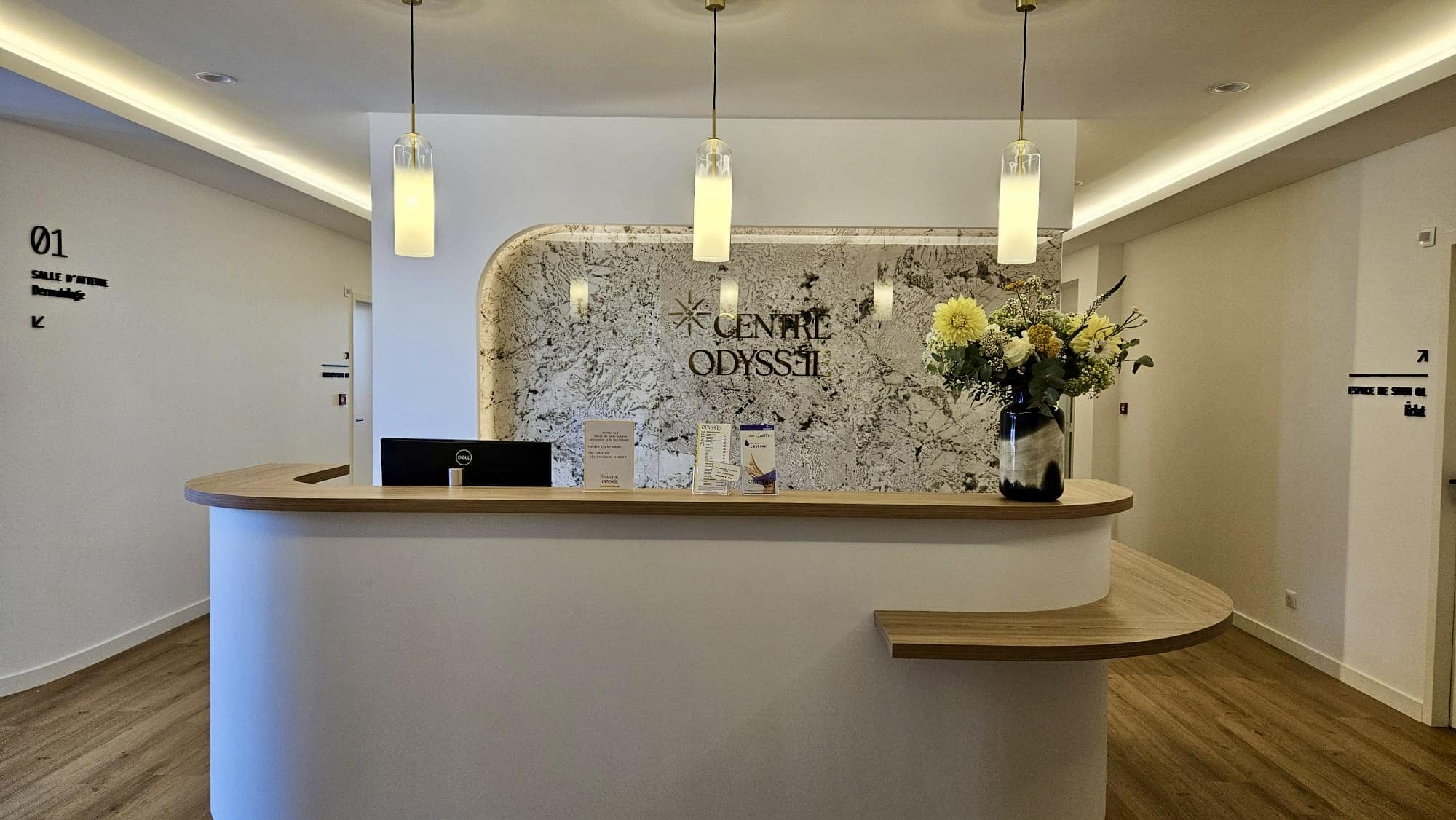 Lettrage mural « Centre Odyssée » installé derrière un comptoir d’accueil médical