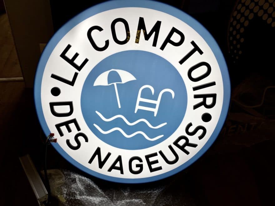 Enseigne lumineuse ronde Le Comptoir des Nageurs avec pictogrammes piscine et parasol