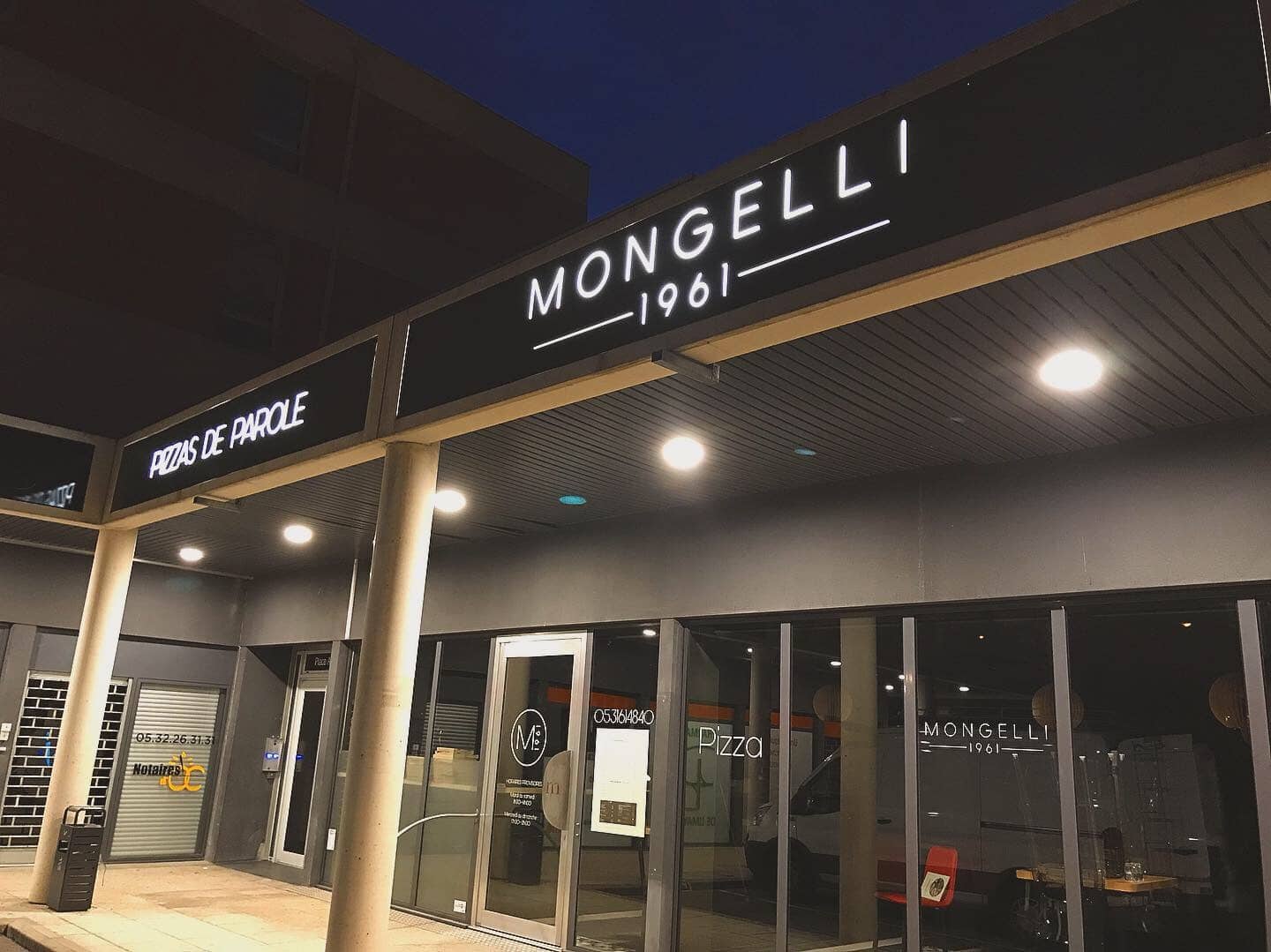 Façade de la pizzeria Mongelli 1961 à Toulouse avec enseigne lumineuse nocturne