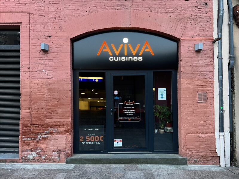 Façade du magasin Aviva Cuisines avec enseigne lumineuse sous arche en brique