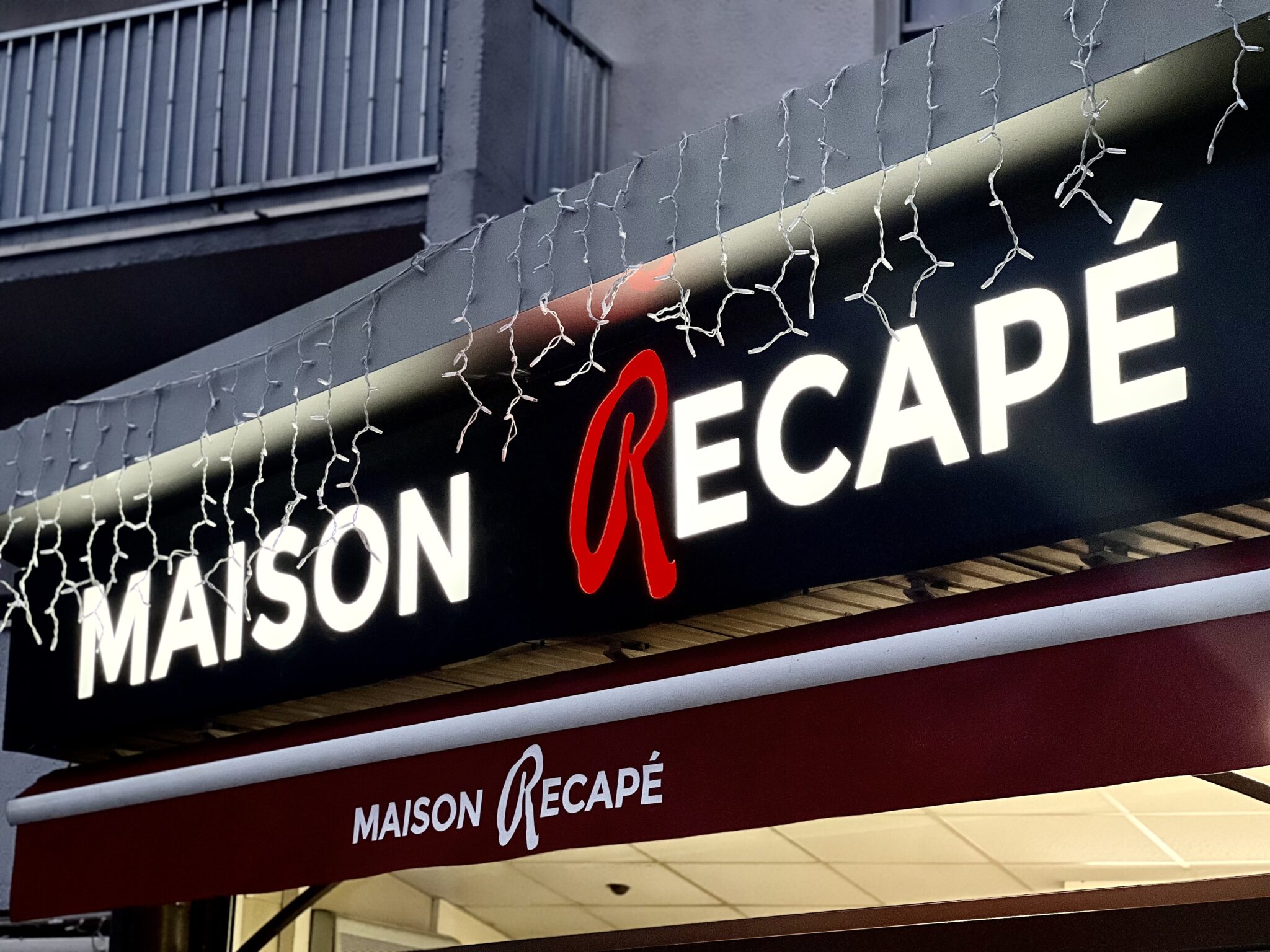 Façade de la boutique Maison Récapé avec enseigne lumineuse et store personnalisé