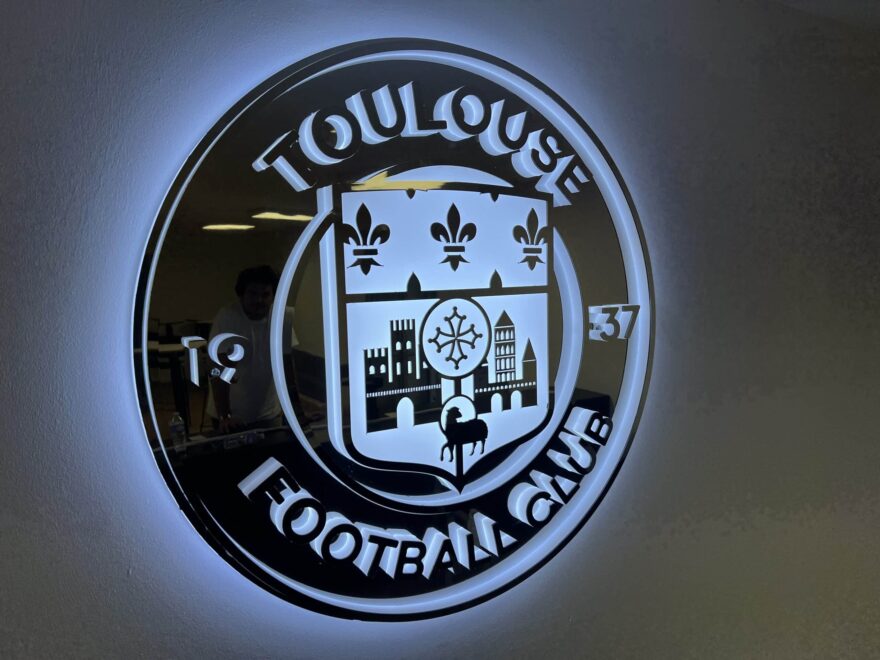 Logo lumineux du Toulouse Football Club rétroéclairé fixé sur mur intérieur