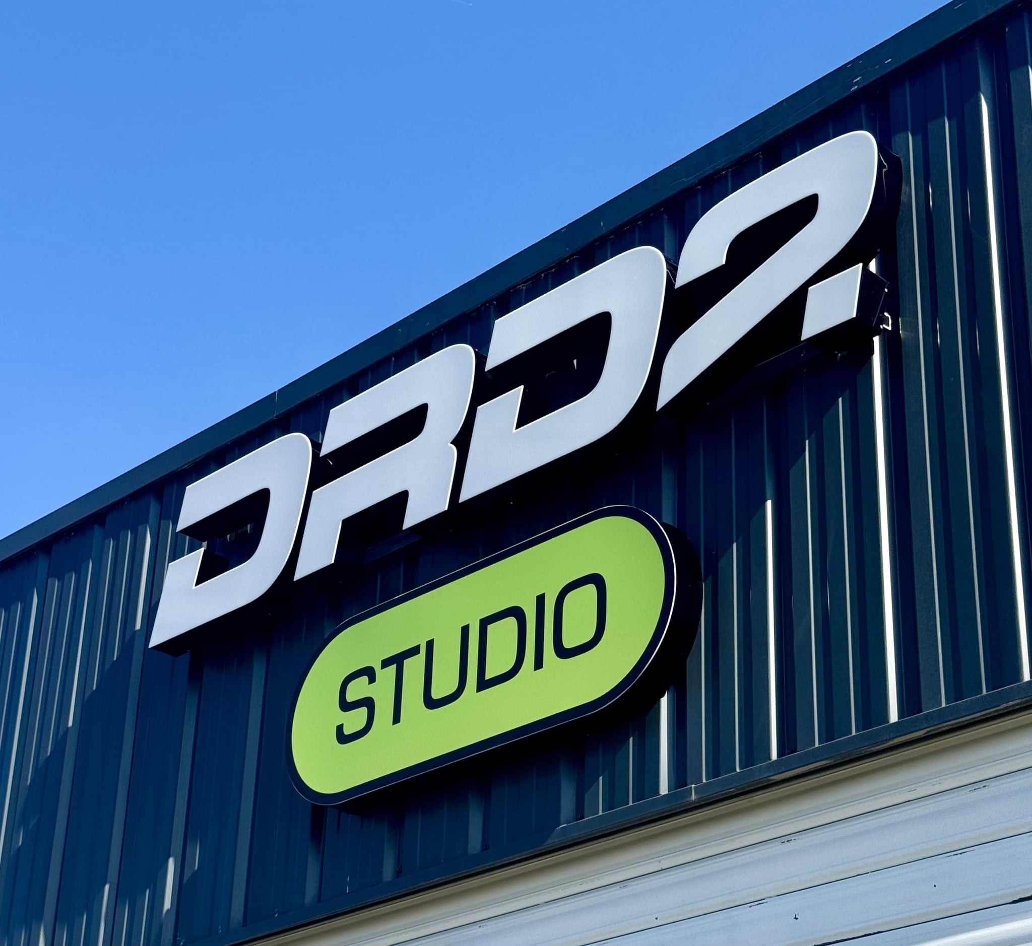 Enseigne DRD7 Studio avec lettres boîtiers blanches et panneau vert rétroéclairé