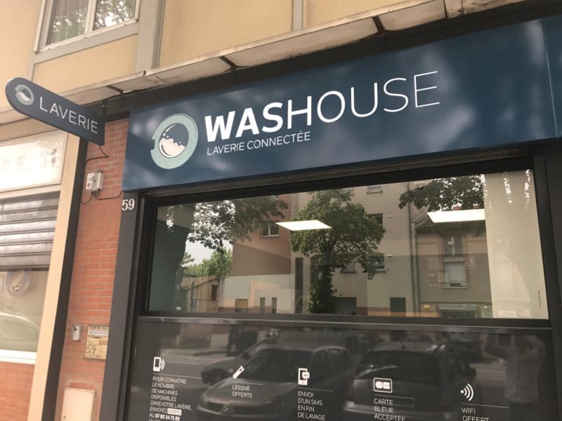 Façade de la laverie Washouse avec enseigne lumineuse et drapeau « Laverie »