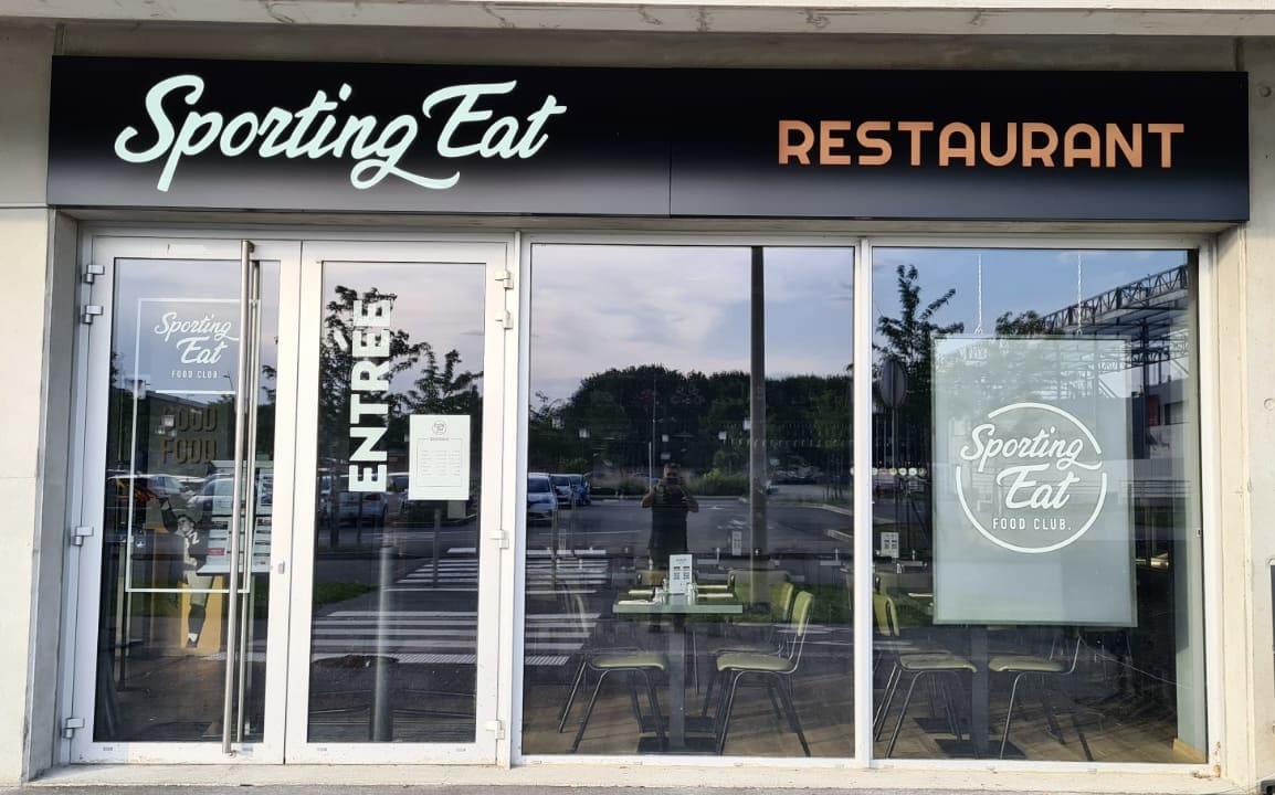 Façade du restaurant Sporting Eat à Toulouse avec enseigne lumineuse et vitrophanie
