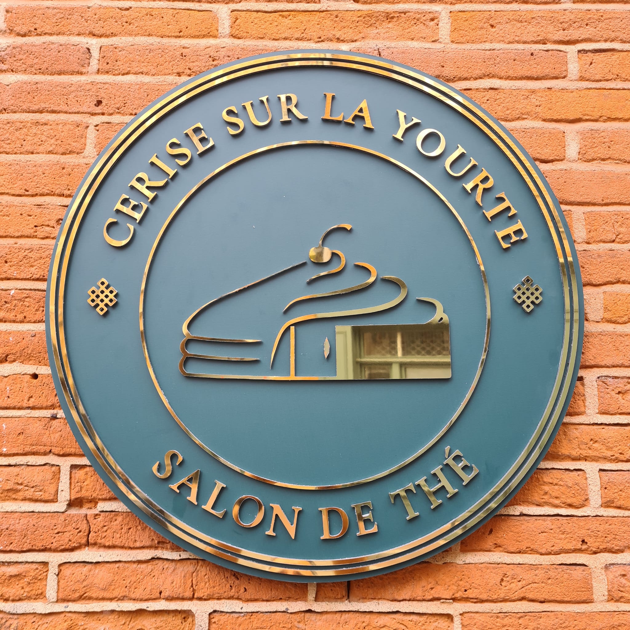 Enseigne murale ronde « Cérise sur la Yourte » avec lettres dorées installée à Toulouse