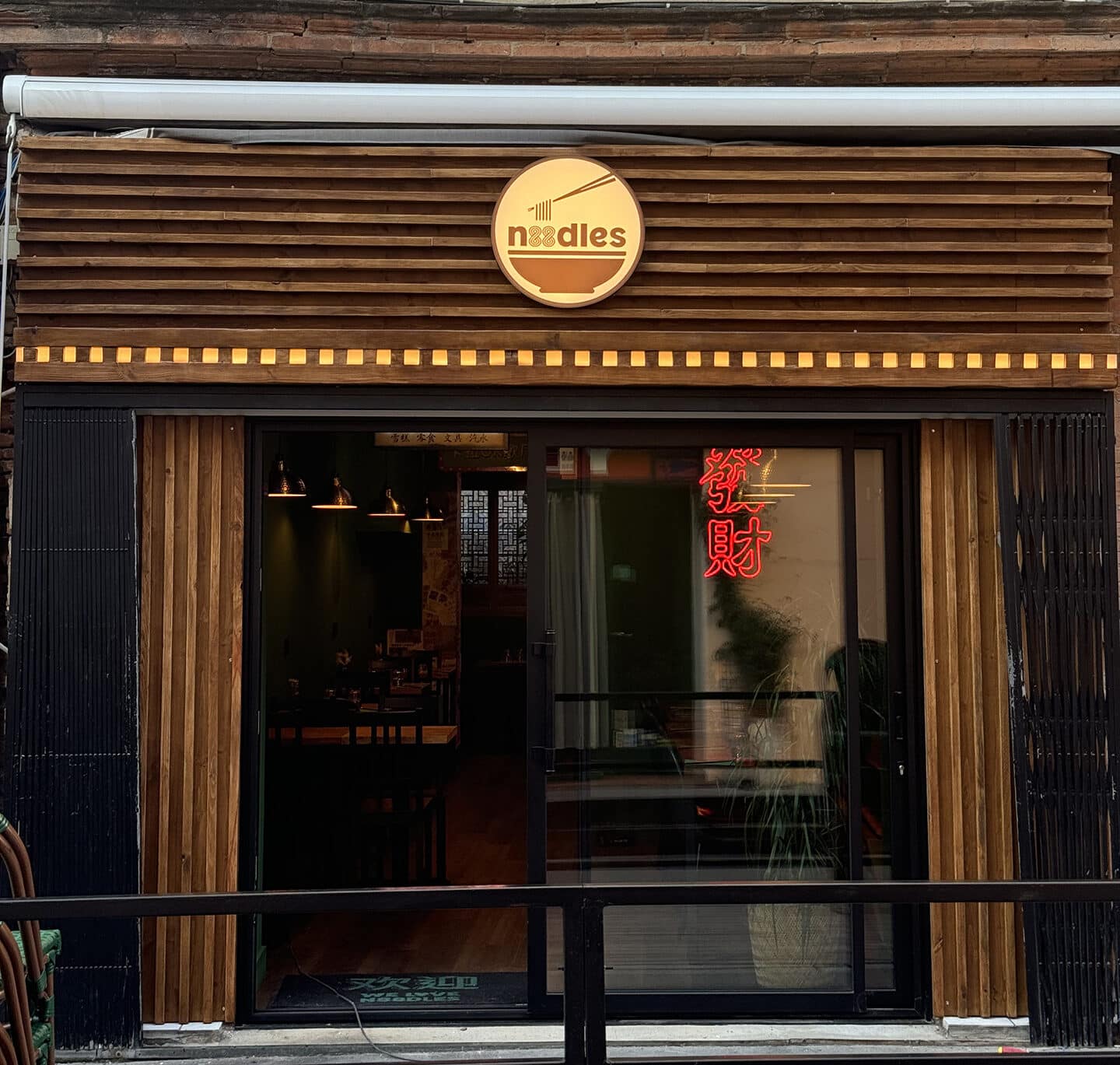 Enseigne lumineuse et habillage façade bois pour le restaurant N88dles à Toulouse. Enseigne publicitaire sur mesure.
